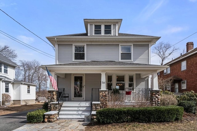 traditional style home with covered porch and roof with shingles