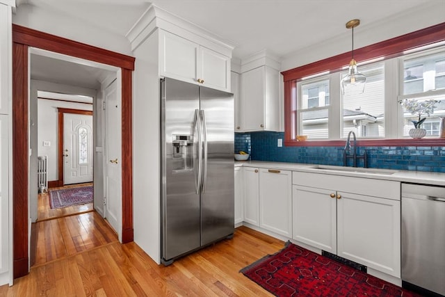 kitchen with light wood-type flooring, light countertops, stainless steel appliances, white cabinetry, and a sink