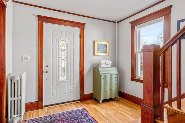 foyer entrance with light wood-type flooring, radiator heating unit, baseboards, and ornamental molding