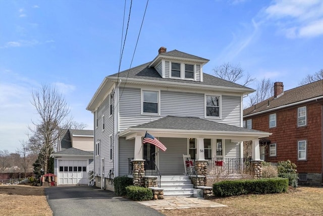 traditional style home with a porch, roof with shingles, a garage, an outdoor structure, and driveway