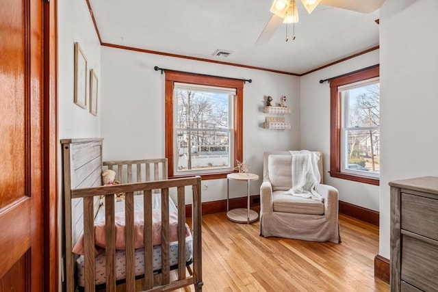 bedroom with visible vents, baseboards, light wood-type flooring, ornamental molding, and a ceiling fan