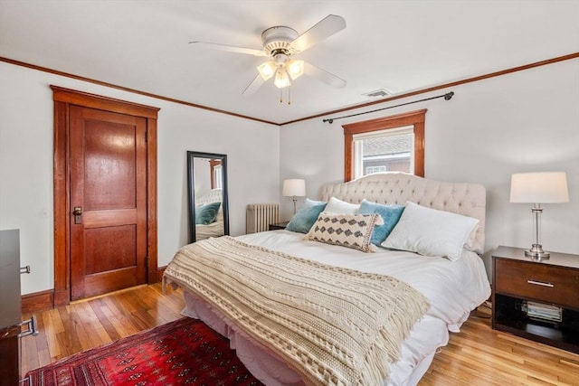 bedroom with light wood-type flooring, visible vents, ornamental molding, radiator, and ceiling fan