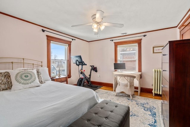 bedroom with multiple windows, wood finished floors, radiator heating unit, and crown molding