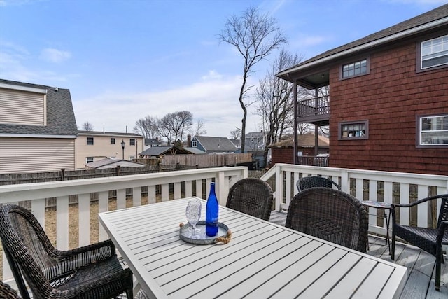 wooden deck featuring a residential view, outdoor dining space, and fence