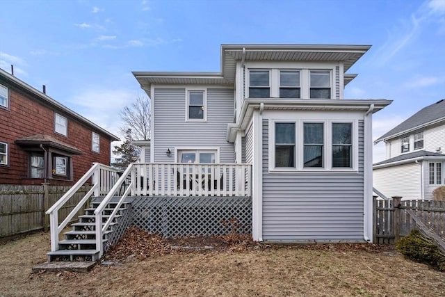 back of property with a deck, stairway, and fence