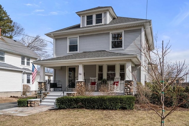 traditional style home with a porch and roof with shingles