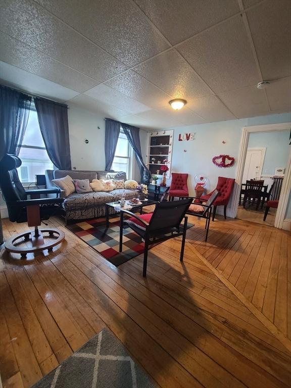 living room with a paneled ceiling and hardwood / wood-style flooring