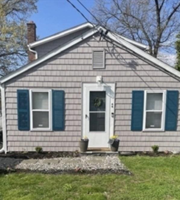 bungalow-style house with a chimney and a front yard