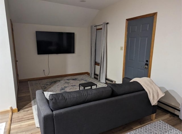 living room with vaulted ceiling, a baseboard heating unit, wood finished floors, and baseboards