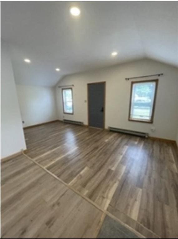 additional living space featuring a baseboard radiator, vaulted ceiling, wood finished floors, and recessed lighting