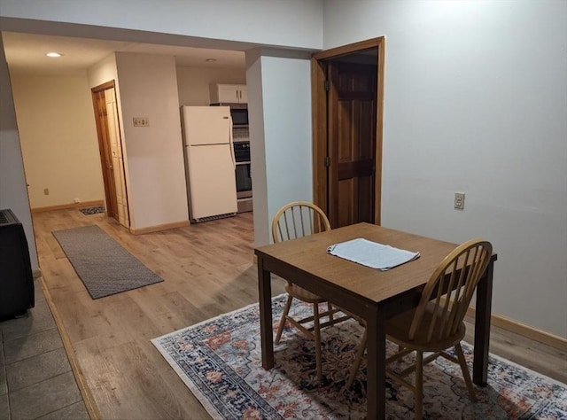 dining space with light wood-type flooring and baseboards