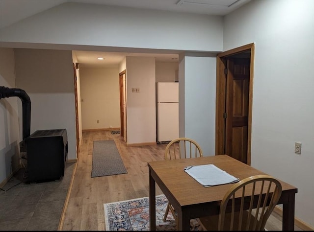 dining room featuring light wood-style floors, baseboards, and vaulted ceiling