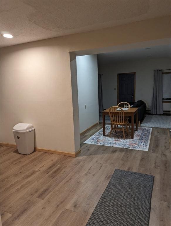 dining space featuring a textured ceiling, wood finished floors, and baseboards