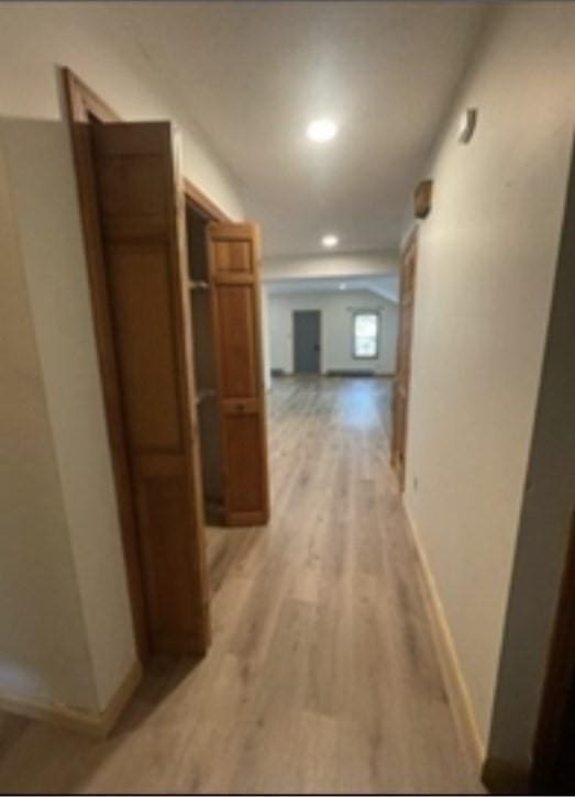 corridor featuring light wood-style flooring and baseboards