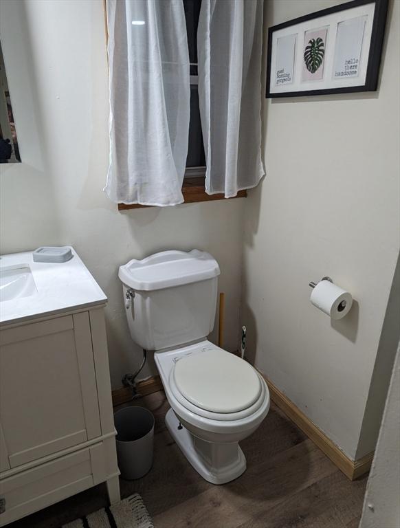 bathroom with toilet, baseboards, wood finished floors, and vanity