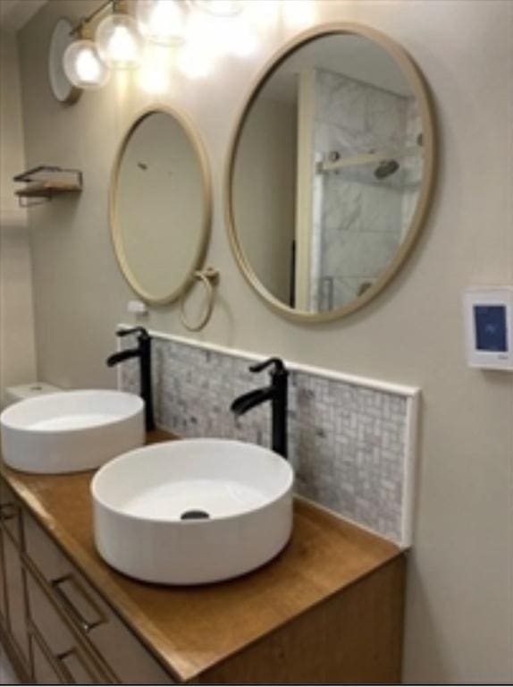 full bath featuring double vanity, decorative backsplash, and a sink