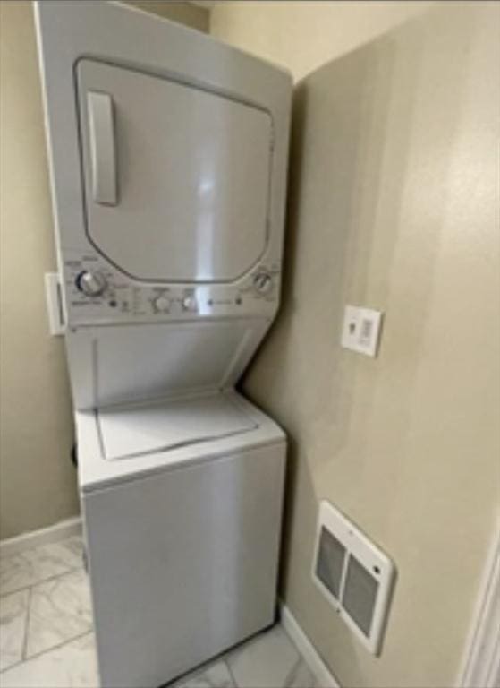 clothes washing area with laundry area, baseboards, visible vents, and stacked washer / dryer