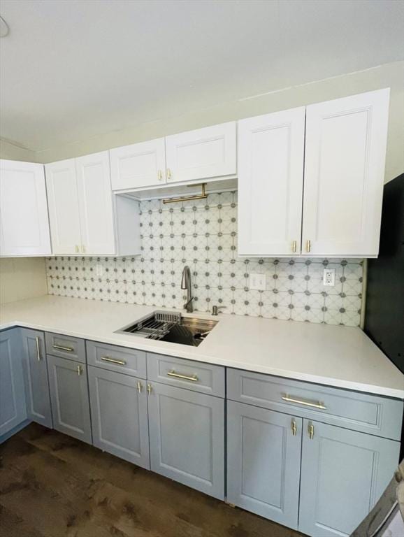 kitchen with tasteful backsplash, light countertops, gray cabinetry, white cabinetry, and a sink