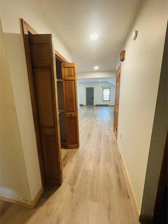 hallway with lofted ceiling, light wood-style flooring, baseboards, and recessed lighting