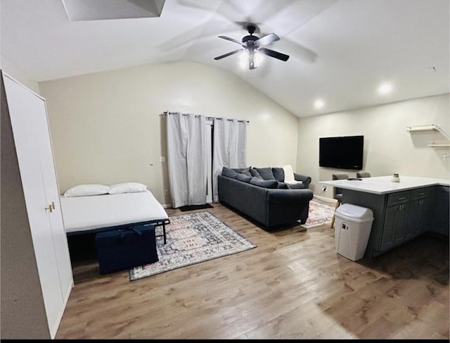 living room with a ceiling fan, vaulted ceiling, and wood finished floors