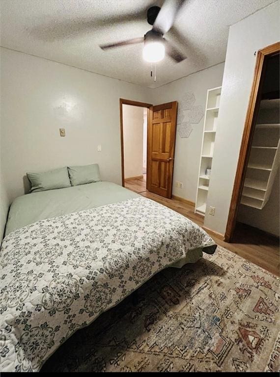 bedroom featuring a ceiling fan, a textured ceiling, and wood finished floors