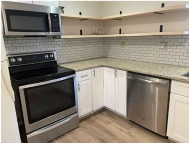 kitchen featuring white cabinetry, appliances with stainless steel finishes, light wood-type flooring, open shelves, and tasteful backsplash