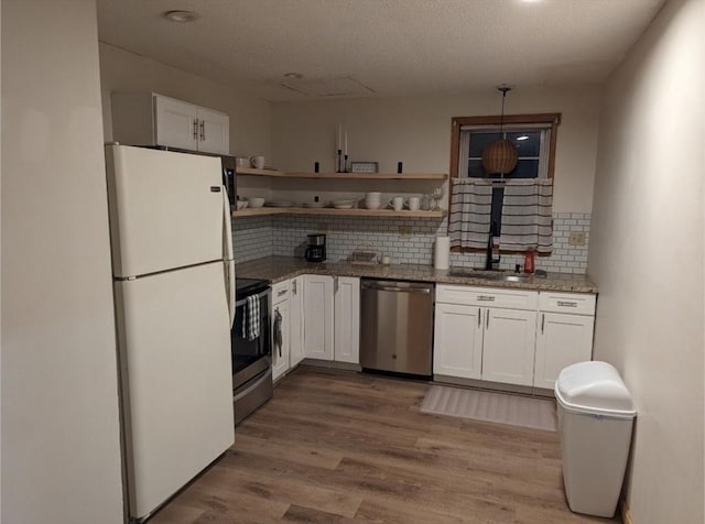 kitchen featuring light wood-style flooring, a sink, white cabinetry, appliances with stainless steel finishes, and open shelves