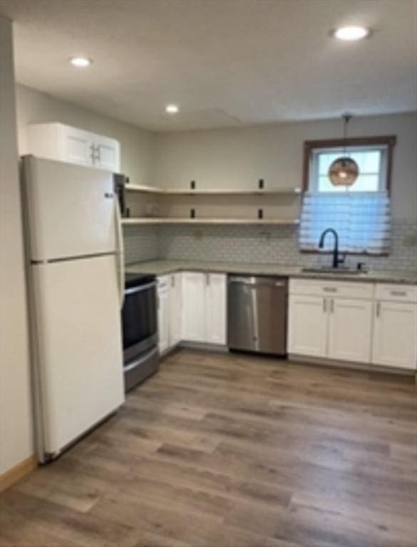 kitchen with open shelves, appliances with stainless steel finishes, white cabinetry, a sink, and wood finished floors