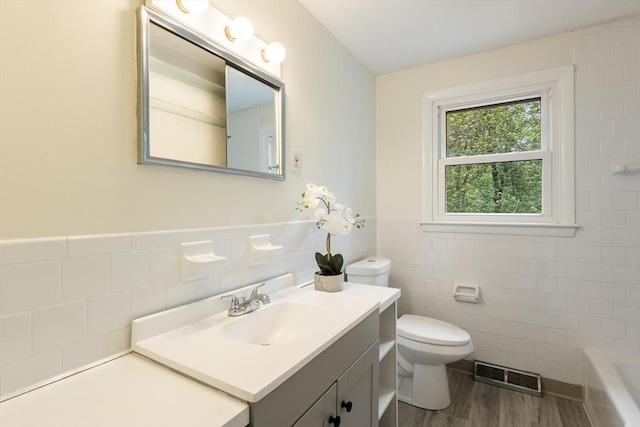 13 Karen Cir, Holliston, MA 01746 - bathroom featuring tile walls, wood finished floors, vanity, a tub to relax in, and toilet