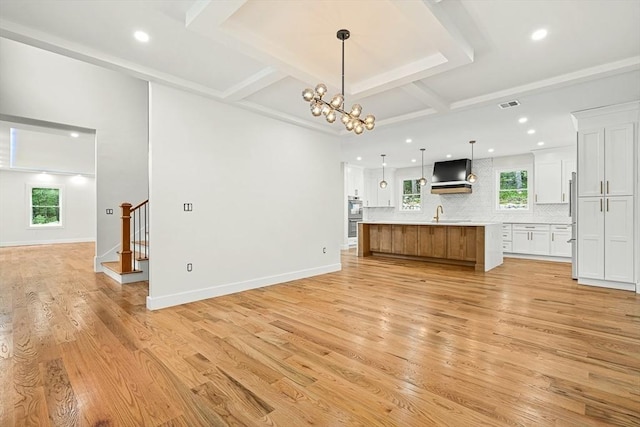 12 Martin St, Carlisle, MA 01741 - unfurnished living room with light wood finished floors, stairway, recessed lighting, beamed ceiling, and a chandelier