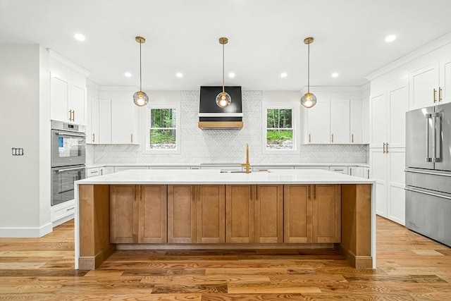 12 Martin St, Carlisle, MA 01741 - kitchen with appliances with stainless steel finishes, light countertops, light wood finished floors, an island with sink, and decorative backsplash