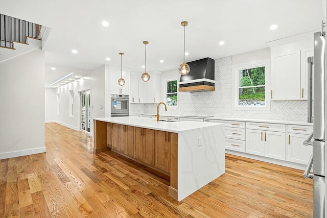 12 Martin St, Carlisle, MA 01741 - kitchen with custom range hood, a kitchen island with sink, tasteful backsplash, light wood-style flooring, and recessed lighting