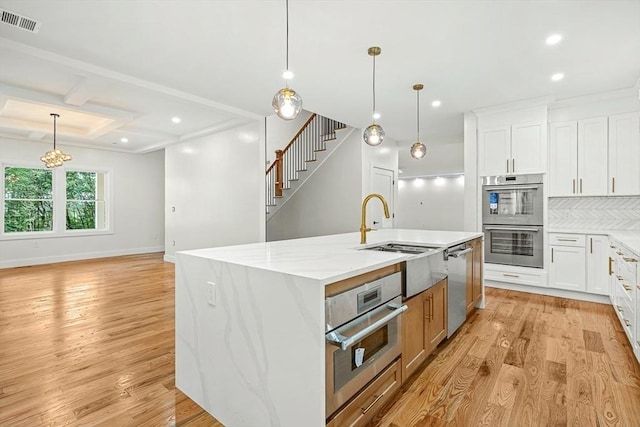 12 Martin St, Carlisle, MA 01741 - kitchen featuring stainless steel appliances, light wood-style floors, a center island with sink, recessed lighting, and light stone counters