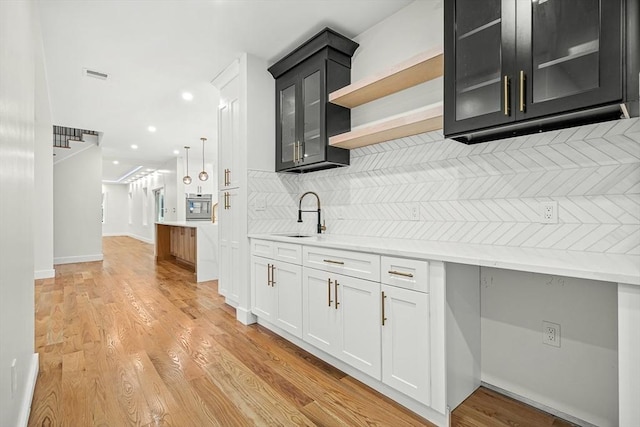 12 Martin St, Carlisle, MA 01741 - bar area featuring decorative backsplash, light wood-style floors, oven, and recessed lighting