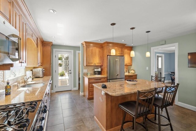16 Bailey Ln, Dedham, MA 02026 - kitchen featuring stainless steel appliances, backsplash, light stone countertops, baseboards, and a center island