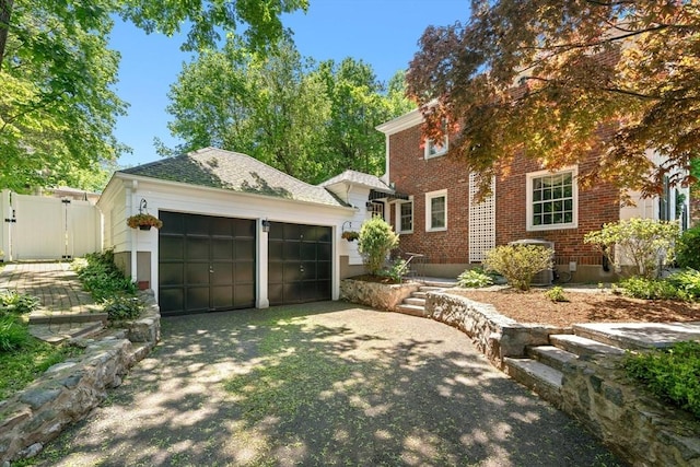 16 Bailey Ln, Dedham, MA 02026 - view of front of house with brick siding, a garage, driveway, a gate, and fence