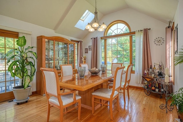 dining room with light wood-type flooring, an inviting chandelier, and lofted ceiling with skylight