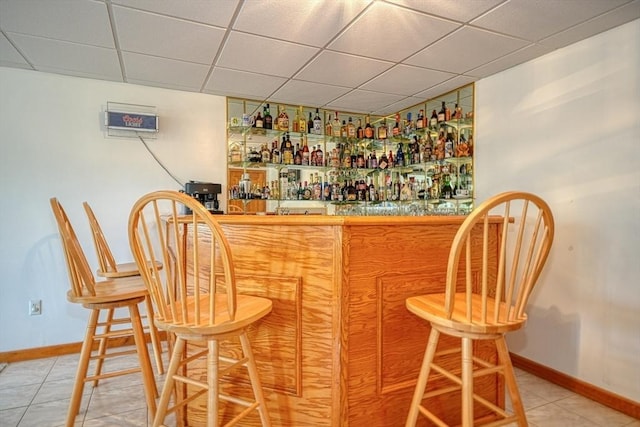 bar with a paneled ceiling and light tile patterned floors