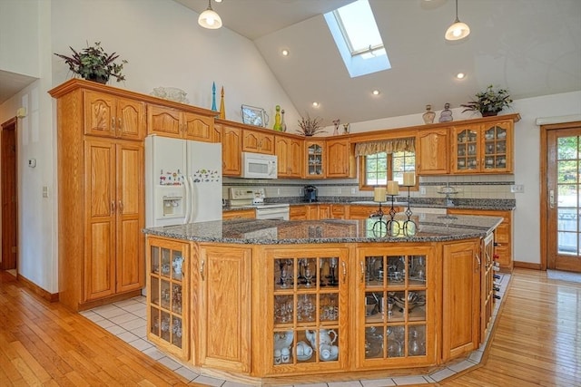 kitchen featuring decorative backsplash, a kitchen island, white appliances, and a skylight