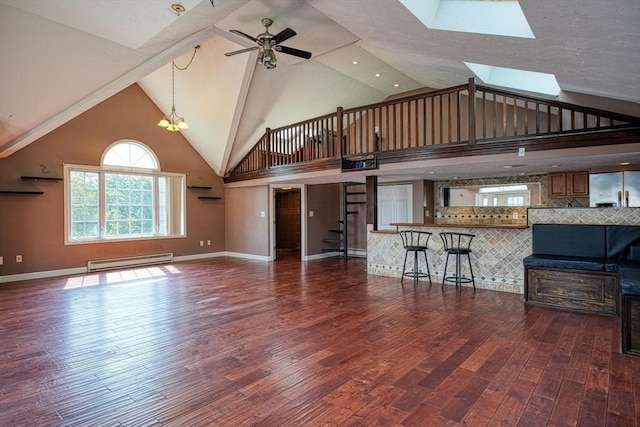 unfurnished living room with a skylight, high vaulted ceiling, dark hardwood / wood-style floors, a baseboard heating unit, and ceiling fan with notable chandelier