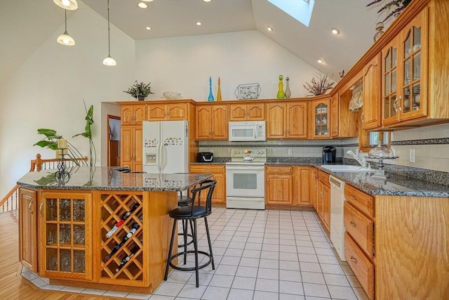 kitchen featuring pendant lighting, decorative backsplash, white appliances, and a skylight