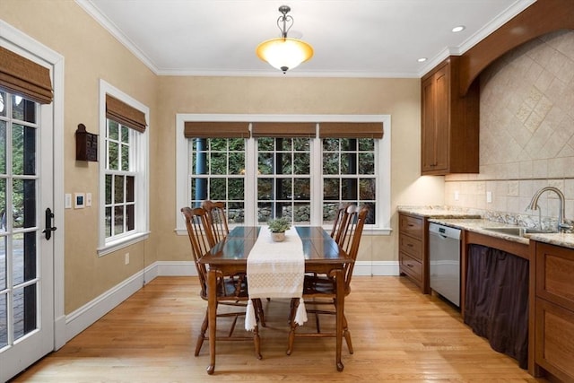 dining space with baseboards, light wood-style flooring, and crown molding