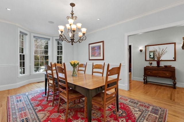 dining area with a notable chandelier, light wood-style flooring, and ornamental molding