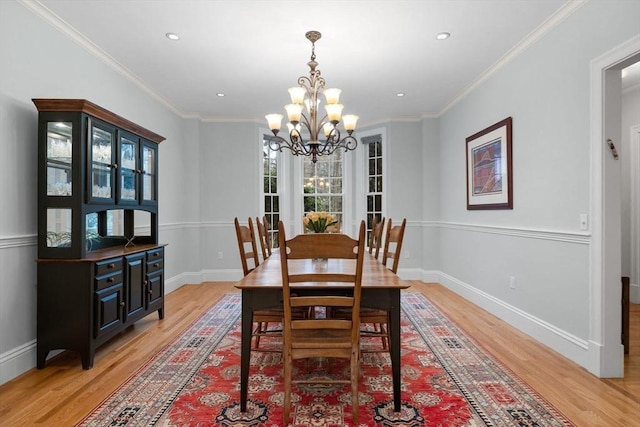 dining area with an inviting chandelier, crown molding, light wood-type flooring, and baseboards