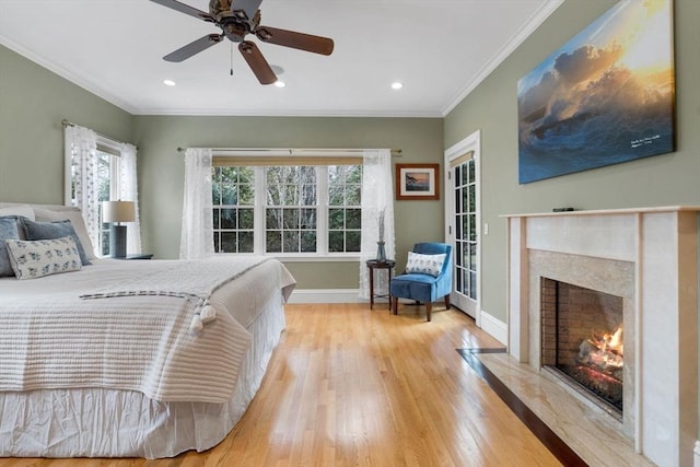 bedroom with crown molding, baseboards, recessed lighting, a fireplace, and wood finished floors