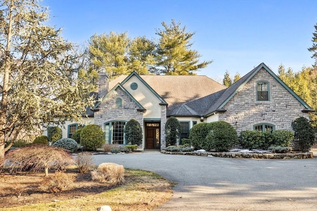 french country home with driveway and a chimney