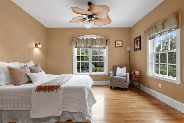 bedroom with baseboards, light wood-style floors, and a ceiling fan