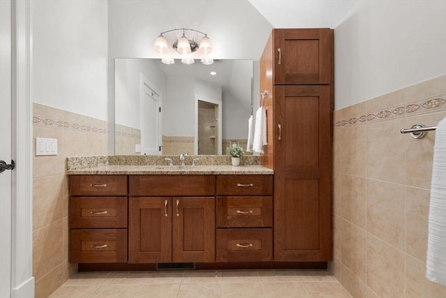 bathroom featuring visible vents, vanity, wainscoting, tile patterned floors, and tile walls