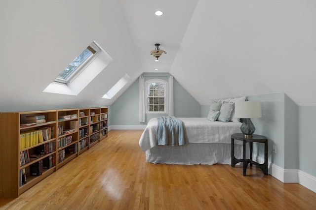 bedroom featuring lofted ceiling with skylight, wood finished floors, and baseboards