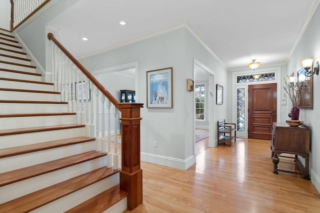 foyer entrance featuring light wood finished floors, crown molding, baseboards, stairway, and recessed lighting